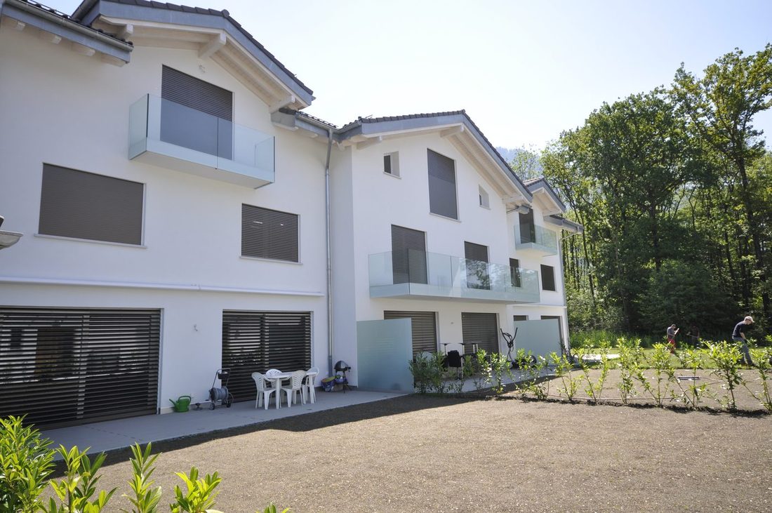 Villas contiguës neuves, façades blanches, balcons vitrés et jardin en cours d'aménagement