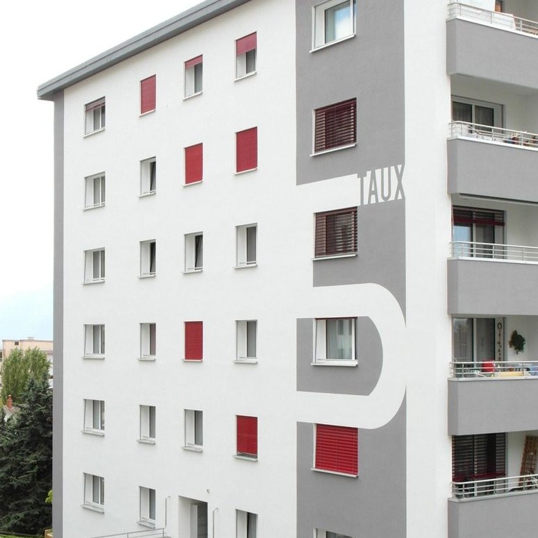Immeuble Taux 5 à Montreux après rénovation : façade isolée, crépi blanc et gris, stores rouges